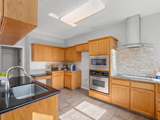 kitchen with sink, dark stone counters, stainless steel appliances, decorative backsplash, and wall chimney range hood