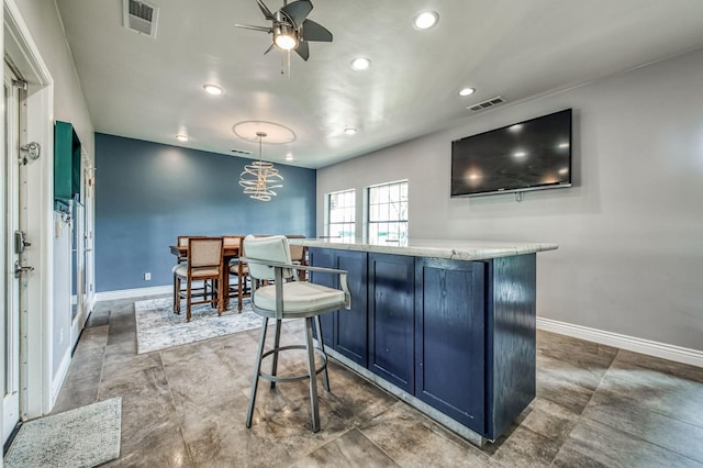 bar with blue cabinetry, ceiling fan, and hanging light fixtures