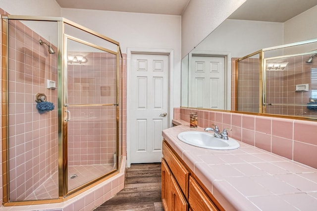 bathroom with tasteful backsplash, hardwood / wood-style floors, vanity, and a shower with shower door