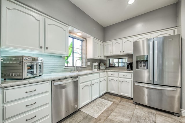 kitchen with white cabinets, stainless steel appliances, tasteful backsplash, and sink