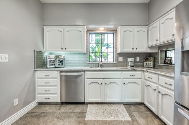 kitchen with decorative backsplash, stainless steel appliances, white cabinetry, and sink