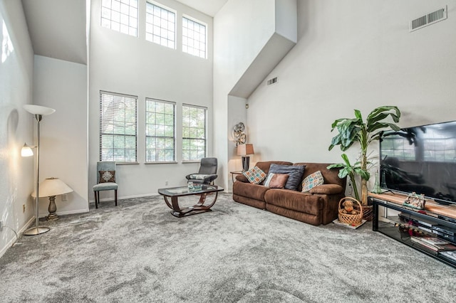 carpeted living room featuring a towering ceiling and a healthy amount of sunlight