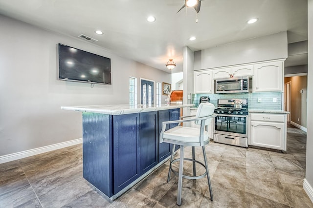 kitchen with backsplash, white cabinets, a kitchen bar, kitchen peninsula, and stainless steel appliances