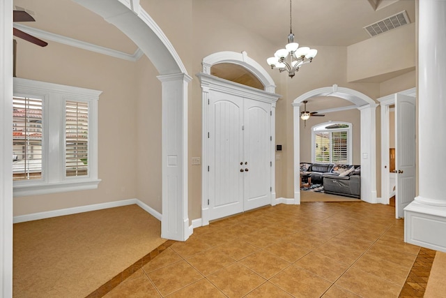 foyer with light tile patterned floors, ceiling fan with notable chandelier, ornate columns, and crown molding