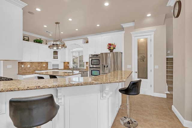 kitchen with pendant lighting, white cabinets, ornamental molding, and appliances with stainless steel finishes