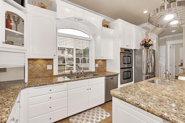 kitchen with appliances with stainless steel finishes, crown molding, sink, pendant lighting, and white cabinetry