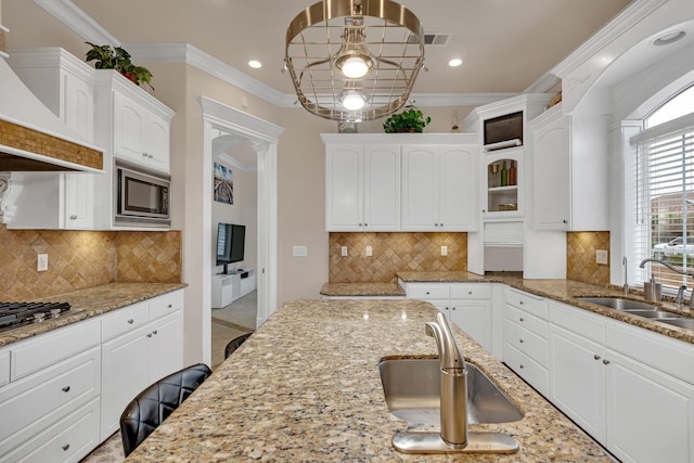 kitchen featuring white cabinets, stainless steel appliances, light stone counters, and ornamental molding