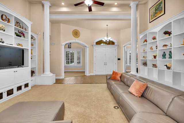 tiled living room with ceiling fan with notable chandelier and ornate columns