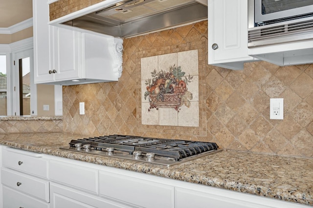 kitchen featuring stainless steel gas stovetop, custom exhaust hood, white cabinetry, and backsplash