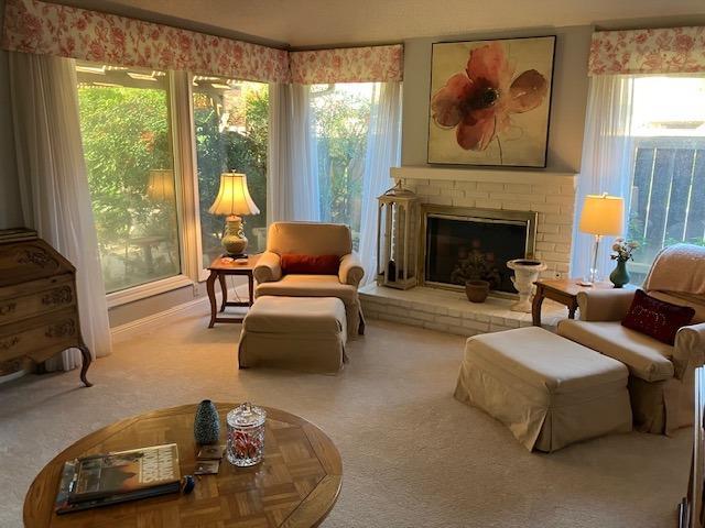 living area with light carpet, a brick fireplace, and a wealth of natural light