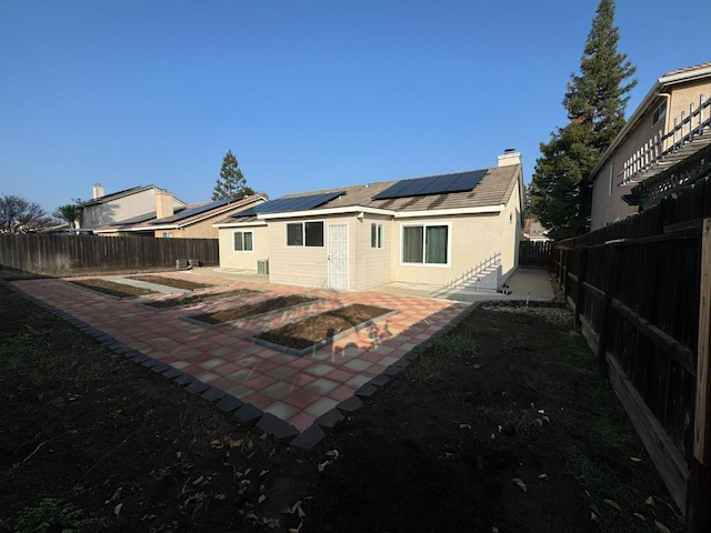 rear view of house featuring a patio area and solar panels