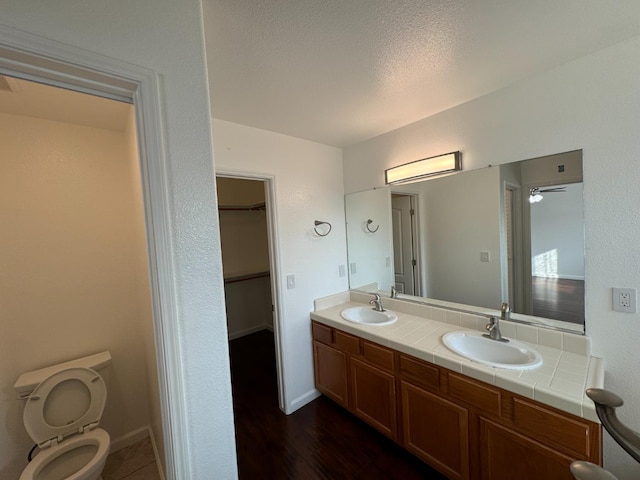 bathroom featuring vanity, hardwood / wood-style flooring, ceiling fan, toilet, and a textured ceiling