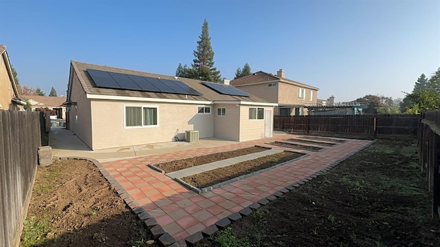 back of house featuring central air condition unit, a patio, and solar panels