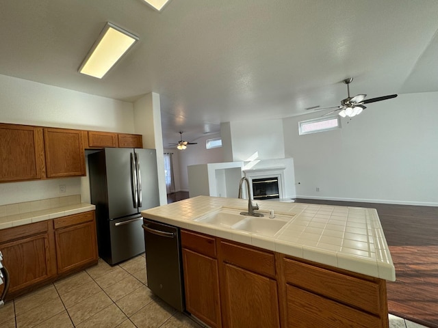 kitchen with ceiling fan, tile counters, sink, stainless steel appliances, and light tile patterned floors