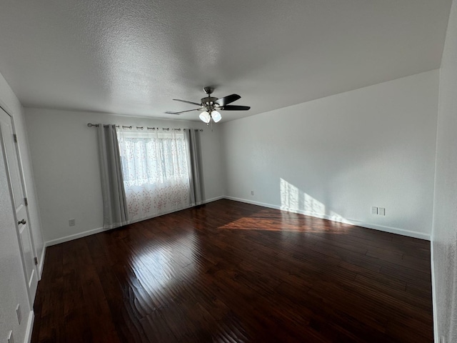 empty room featuring a textured ceiling, ceiling fan, and dark wood-type flooring