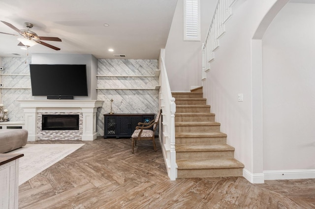 living area with arched walkways, recessed lighting, visible vents, baseboards, and stairway