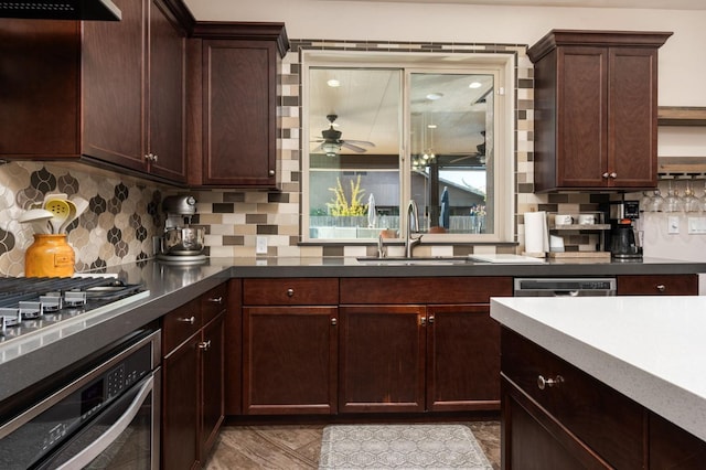 kitchen with stainless steel appliances, a sink, ceiling fan, and tasteful backsplash