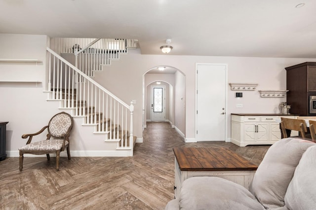 foyer featuring arched walkways, stairway, and baseboards