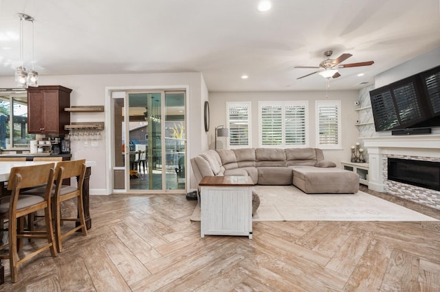 living area featuring a wealth of natural light, ceiling fan, a stone fireplace, and recessed lighting