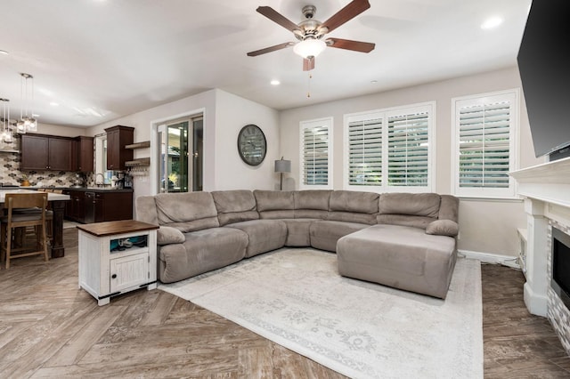 living area featuring a healthy amount of sunlight, a fireplace, baseboards, and a ceiling fan