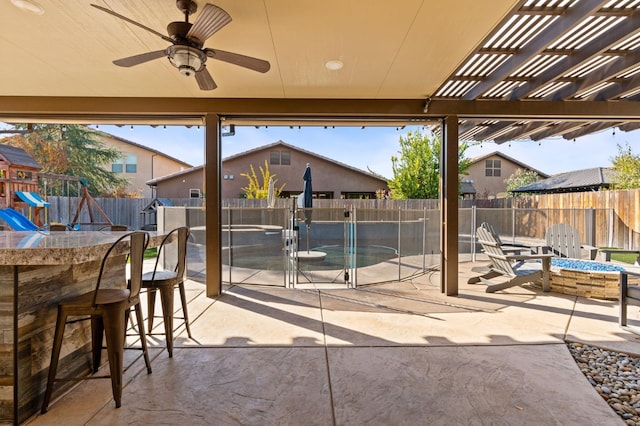 view of patio / terrace with a playground, outdoor dry bar, an outdoor fire pit, a pergola, and a fenced backyard