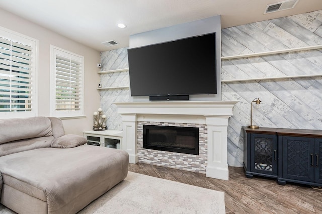 living area with visible vents, wood finished floors, and a glass covered fireplace