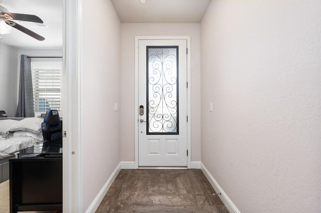 doorway featuring ceiling fan and baseboards