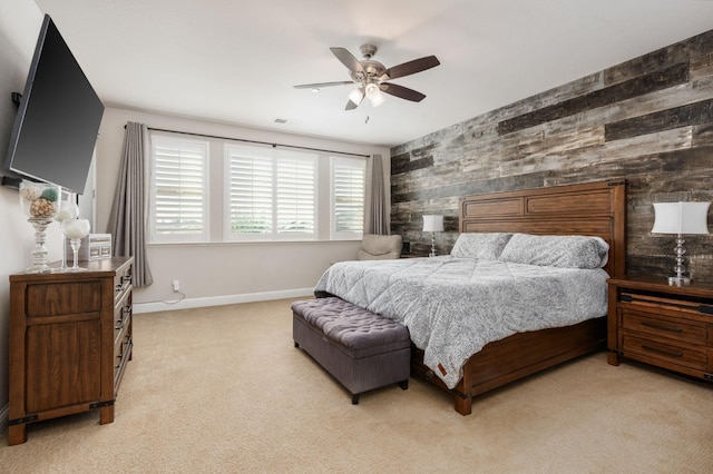 bedroom with light carpet, visible vents, baseboards, a ceiling fan, and an accent wall