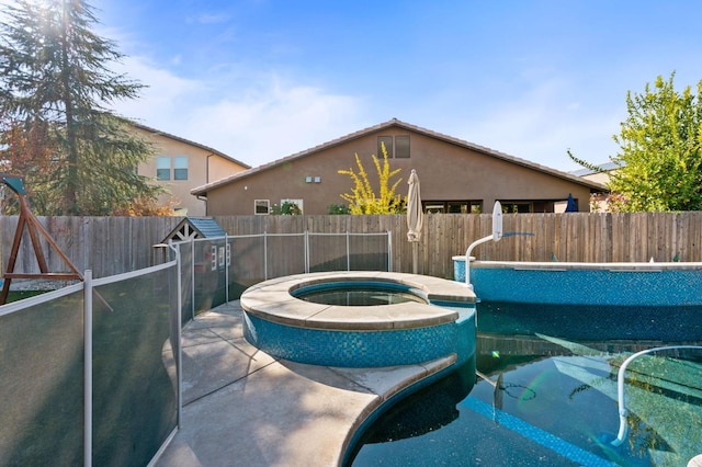 view of swimming pool with a fenced backyard and a pool with connected hot tub