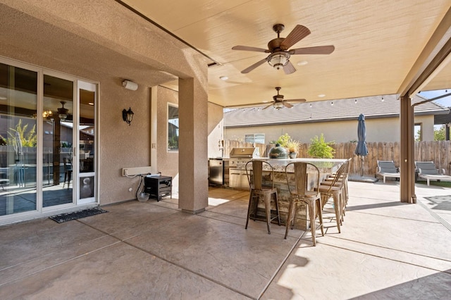 view of patio / terrace with grilling area, fence, an outdoor kitchen, and a ceiling fan