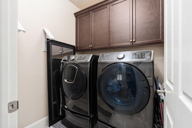 washroom featuring separate washer and dryer, cabinet space, and baseboards