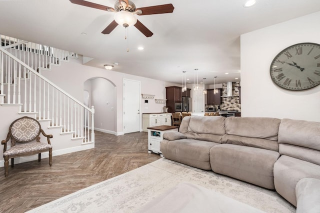 living area featuring baseboards, stairway, arched walkways, and recessed lighting