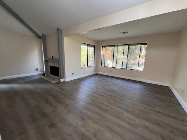 unfurnished living room with dark wood-type flooring and a tile fireplace