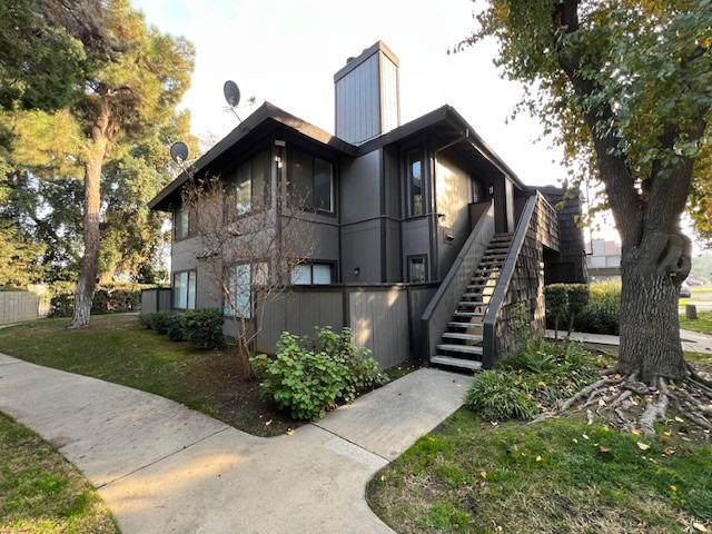 view of side of property with stairs and a lawn