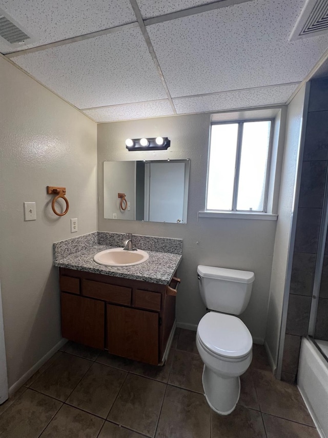 full bathroom with a drop ceiling, tile patterned flooring, toilet, vanity, and shower / bathtub combination