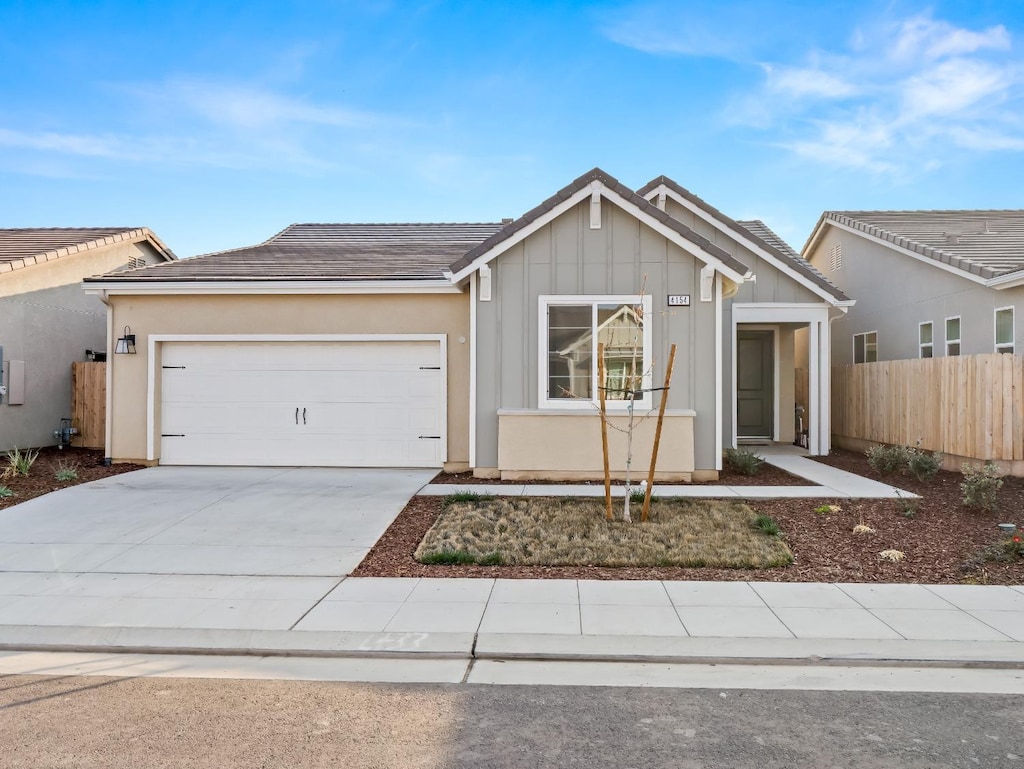 single story home featuring an attached garage, fence, concrete driveway, stucco siding, and board and batten siding