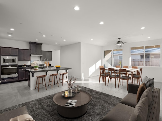 living room with sink, light tile patterned flooring, and a chandelier