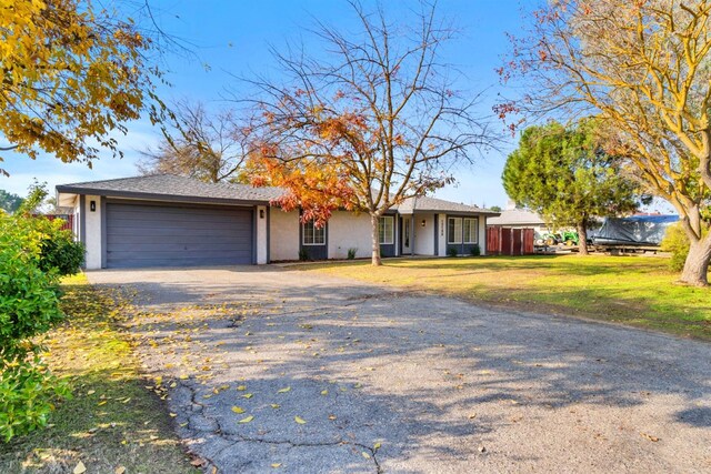 ranch-style home featuring a garage and a front lawn