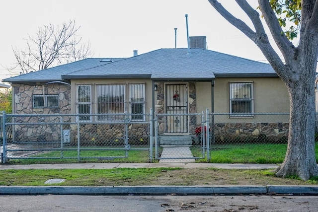 bungalow-style home with a shingled roof, stone siding, a fenced front yard, a gate, and stucco siding