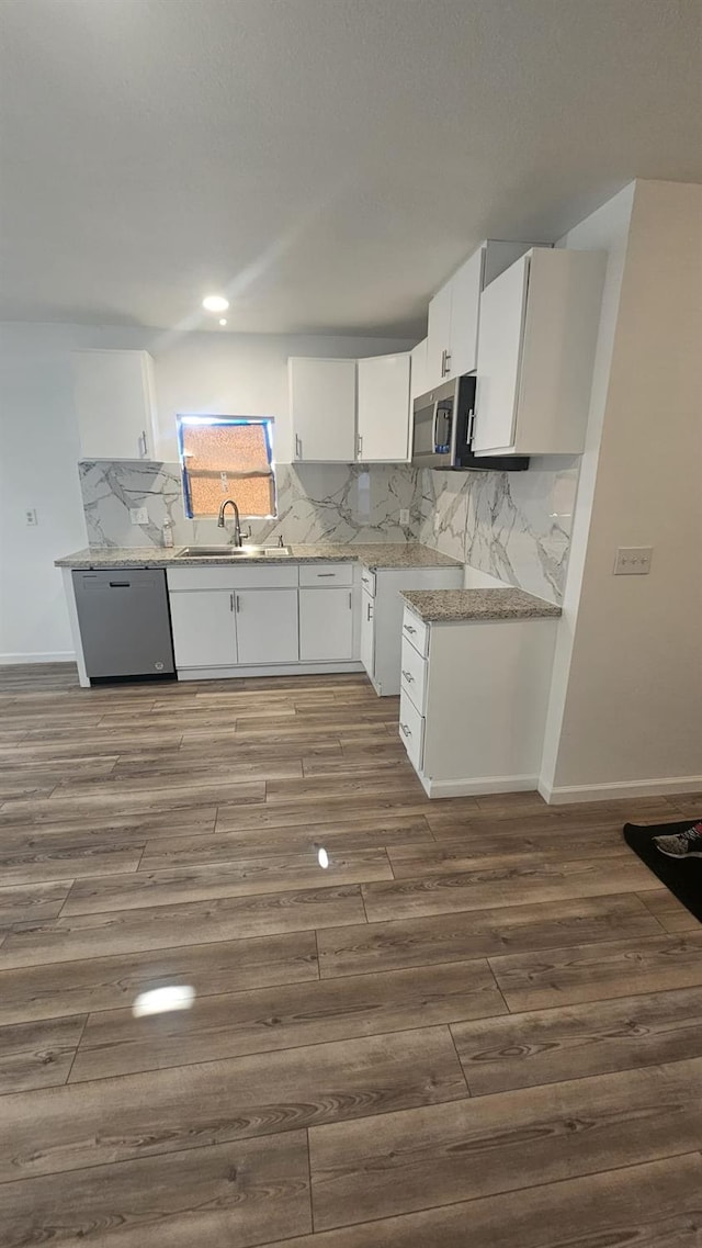 kitchen with white cabinetry, sink, stainless steel appliances, dark hardwood / wood-style flooring, and backsplash