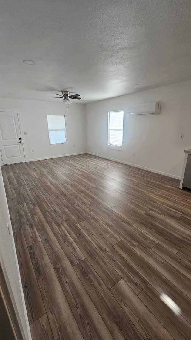 spare room with a wall mounted air conditioner, a textured ceiling, dark hardwood / wood-style flooring, and ceiling fan