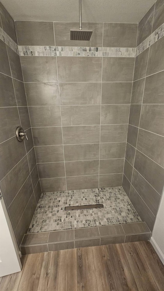 bathroom with hardwood / wood-style flooring and a tile shower