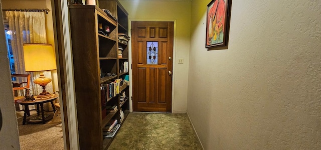 entryway featuring a textured wall and baseboards