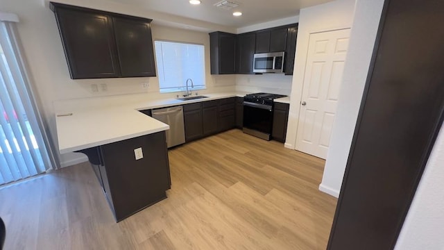 kitchen with a breakfast bar, sink, light hardwood / wood-style floors, kitchen peninsula, and stainless steel appliances