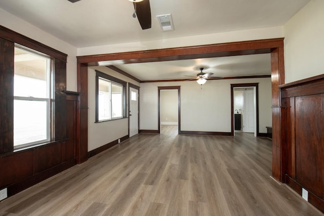 unfurnished living room featuring hardwood / wood-style floors, ceiling fan, and crown molding