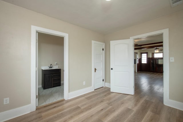 unfurnished bedroom with ensuite bath, light hardwood / wood-style flooring, and sink