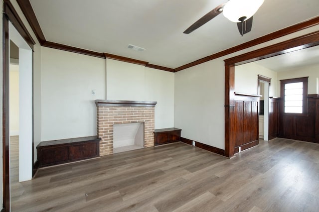 unfurnished living room featuring a brick fireplace, crown molding, ceiling fan, and hardwood / wood-style flooring