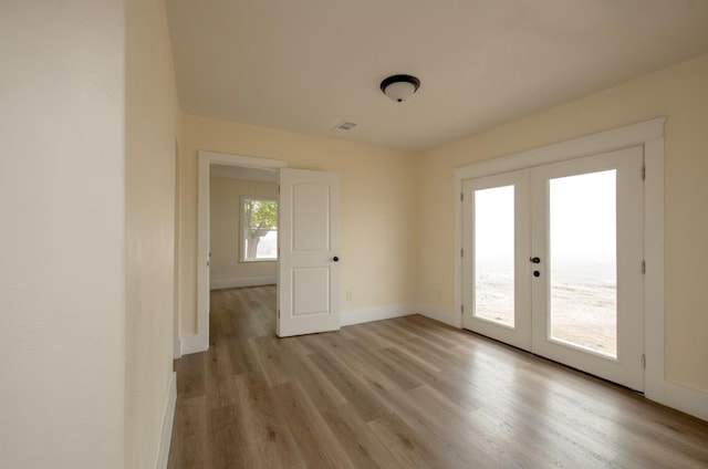 spare room featuring french doors and light hardwood / wood-style flooring