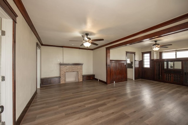 unfurnished living room with crown molding, a fireplace, ceiling fan, and dark wood-type flooring