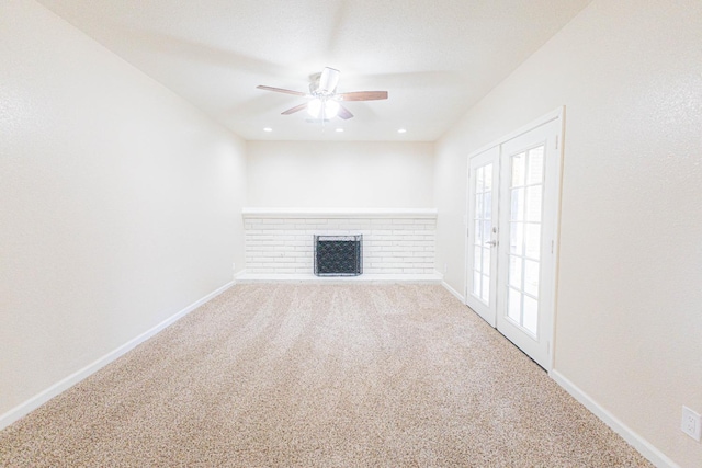 unfurnished living room with carpet flooring, a fireplace, ceiling fan, and french doors